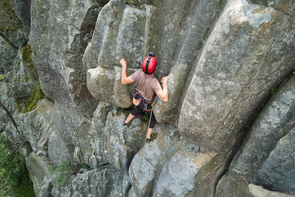 Junger Mann klettert steile Felswand hinauf. Männlicher Bergsteiger bewältigt anspruchsvolle Route Engagement im Extremsportkonzept — Stockfoto