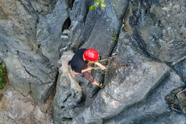 Young man climbing steep wall of rocky mountain. Male climber overcomes challenging route. Engaging in extreme sport concept — Stock Photo, Image