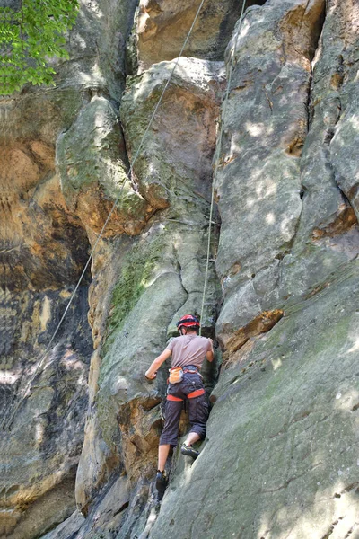 年轻人爬上陡峭的岩石山墙.男性攀登者克服了具有挑战性的路线。参与极端体育概念 — 图库照片