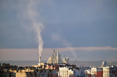 Yüksek fabrika yapısına sahip çimento fabrikası ve şehir merkezi yakınlarındaki endüstriyel üretim alanındaki vinçler. Üretim ve küresel sanayi kavramı