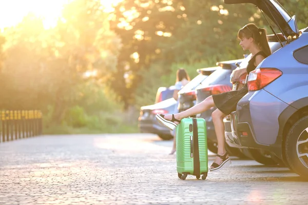 Una joven con una maleta esperando cerca de su coche. Concepto de viajes y vacaciones — Foto de Stock