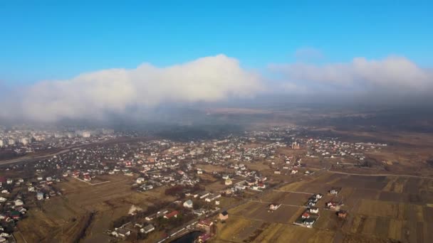 Widok z dużej wysokości odległego miasta pokryty burzliwymi chmurami kumulującymi przelatujące przed burzą. Punkt widzenia samolotu na krajobraz w pochmurną pogodę — Wideo stockowe