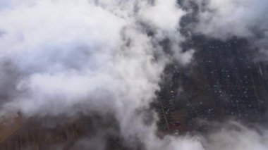 Fırtınadan önce, şişkin kümülüs bulutlarıyla kaplı uzak şehrin yüksek irtifasından gelen hava manzarası. Bulutlu havada uçak manzarası