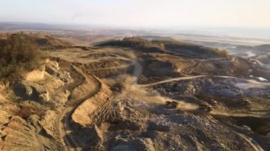Kazı makineleri ve çöp kamyonlarıyla inşaat endüstrisi için kumtaşı malzemelerinden oluşan açık maden manzarası. Madencilik ve kullanışlı mineral üretiminde ağır ekipman