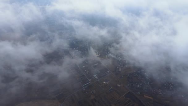 Vista aérea desde gran altitud de la ciudad distante cubierta de nubes de cúmulos hinchados que pasan volando antes de la tormenta. Avión punto de vista del paisaje en tiempo nublado — Vídeos de Stock