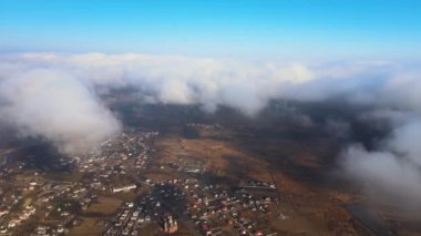 Yağmurdan önce oluşan kabarık kümülüs bulutlarıyla kaplı uzak şehrin yüksek irtifasından hava manzarası. Bulutlu manzaraya uçak bakışı