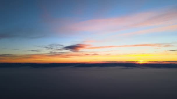 Veduta aerea del tramonto colorato su bianco densa nebbia nuvole coprire con sagome scure distanti di colline di montagna all'orizzonte — Video Stock