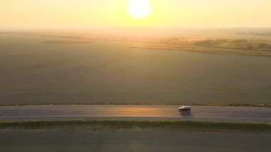 Gün batımında hızlı giden arabalarla şehirlerarası yol manzarası. Akşamları otoban trafiğinin insansız hava aracı görüntüsü