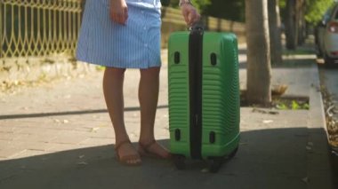 Genç kadın sürücü yeşil bavulu şehir caddesindeki çatı rafına koyuyor. Seyahat ve tatil kavramı