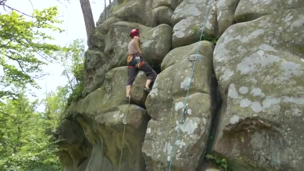 Fiatalember mászik meredek fal sziklás hegy. A férfi hegymászó legyőzi a kihívást jelentő utat. Szélsőséges sportkoncepció alkalmazása — Stock videók