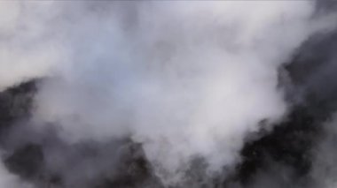 Yağmurdan önce oluşan kabarık kümülüs bulutlarıyla kaplı uzak şehrin yüksek irtifasından hava manzarası. Bulutlu manzaraya uçak bakışı