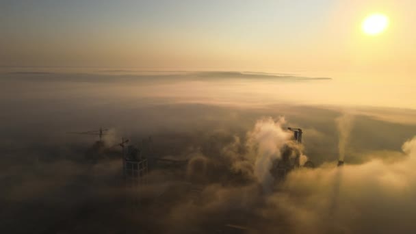 Aerial view of cement factory with high concrete plant structure and tower crane at industrial manufacturing site on foggy evening. Production and global industry concept — Stock Video