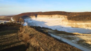 Kazı makineleri ve çöp kamyonlarıyla inşaat endüstrisi için kumtaşı malzemelerinden oluşan açık maden manzarası. Madencilik ve kullanışlı mineral üretiminde ağır ekipman