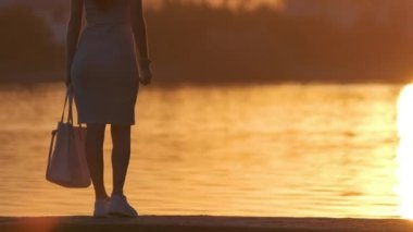 Sıcak bir akşamda göl kıyısında tek başına duran yalnız bir kadın. Yalnızlık ve doğa konseptinde rahatlama.