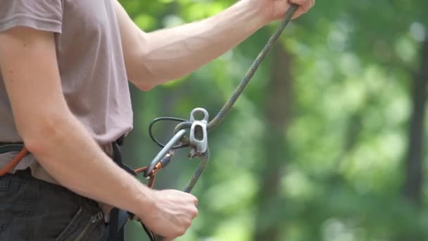 Man belays rekannya pendaki dengan perangkat belaying dan tali. Handsman memanjat tebing memegang peralatan untuk keamanan pendakian batu — Stok Video