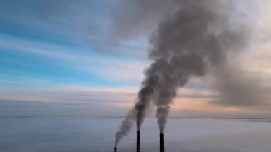 Kömür santralinin hava manzarası siyah dumanlı yüksek borular gün batımında atmosferi kirletiyor