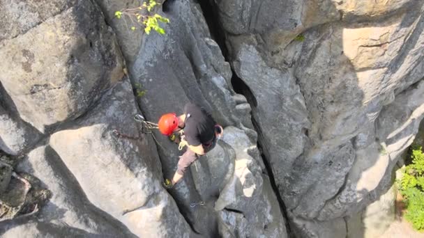 Fiatalember mászik meredek fal sziklás hegy. A férfi hegymászó legyőzi a kihívást jelentő utat. Szélsőséges sportkoncepció alkalmazása — Stock videók