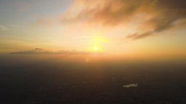 Akşamları yağmur fırtınasından önce oluşan kabarık kümülüs bulutlarıyla kaplı uzak şehrin yüksek irtifasından hava manzarası. Bulutlu manzaraya uçak bakışı