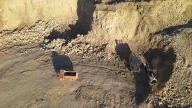 Kazı makineleri ve çöp kamyonlarıyla inşaat endüstrisi için kumtaşı malzemelerinden oluşan açık maden manzarası. Madencilik ve kullanışlı mineral üretiminde ağır ekipman
