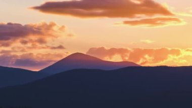 Güzel bir akşam panoramik manzarası. Gün batımında uzak dağ tepeleri üzerinde parlak batan güneş.
