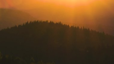 Güzel bir akşam panoramik manzarası. Gün batımında uzak dağ tepeleri üzerinde parlak batan güneş.