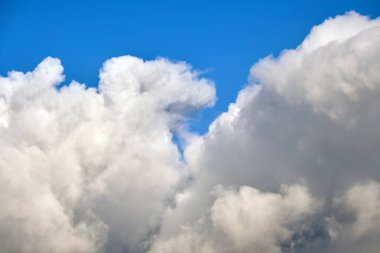 Açık mavi gökyüzünde beyaz kabarık kümülüs bulutlarının parlak manzarası