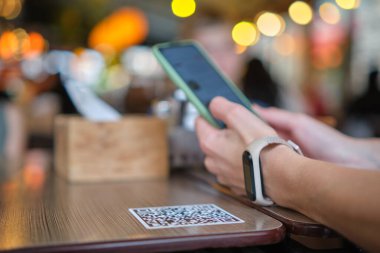 Konuk elin restoranda yemek sipariş ederken çevrimiçi menü için qr kodunu cep telefonuyla taraması