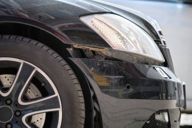 Çamurluğu hasarlı, kaza yapmış bir araba şehrin caddesine park edilmiş. Yol güvenliği ve araç sigortası kavramı