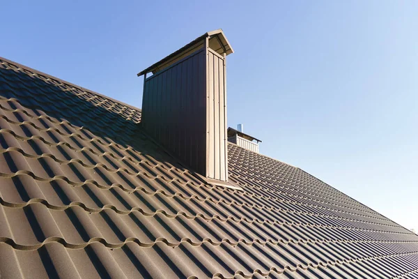 Schornstein auf Hausdach mit Metallschindeln im Bau. Fliesenverkleidung des Gebäudes. Immobilienentwicklung — Stockfoto