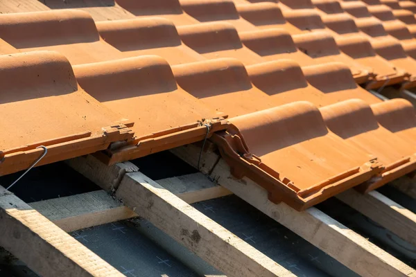 Chevauchement de rangées de tuiles de toiture en céramique jaune montées sur des planches de bois couvrant le toit du bâtiment résidentiel en construction — Photo