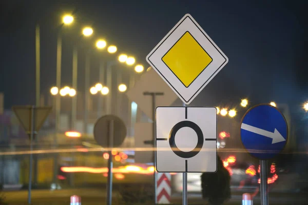 Ранкові дорожні знаки з розмитими автомобілями на міському вуличному трафіку вночі. Концепція міського транспорту — стокове фото