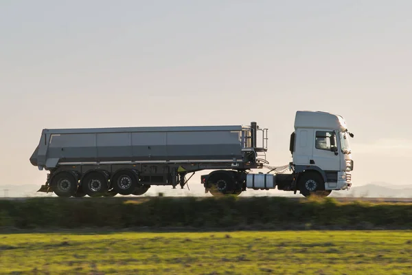 Ημι-φορτηγό με ανατρεπόμενο ρυμουλκούμενο φορτίο μεταφορά άμμου από λατομείο οδήγηση σε αυτοκινητόδρομο μεταφορά εμπορευμάτων το βράδυ. Η έννοια της μεταφοράς και της εφοδιαστικής — Φωτογραφία Αρχείου