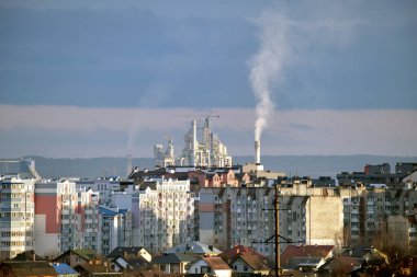 Yüksek fabrika yapısına sahip çimento fabrikası ve şehir merkezi yakınlarındaki endüstriyel üretim alanındaki vinçler. Üretim ve küresel sanayi kavramı