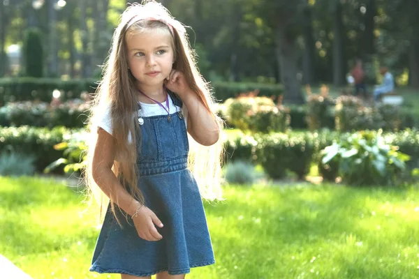 Pequena menina bonita com cabelos longos andando ao ar livre no parque de verão verde em um dia ensolarado — Fotografia de Stock