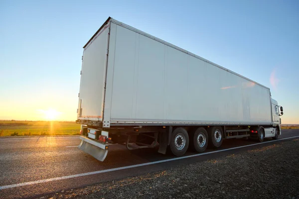 Semi-vrachtwagen met lading aanhangwagen rijden op de snelweg vervoeren goederen in de avond. Levering transport en logistiek concept — Stockfoto
