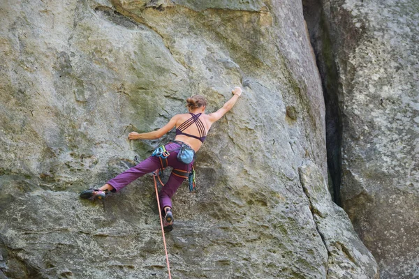 Jovem mulher escalando parede íngreme de montanha rochosa. Menina alpinista supera rota desafiadora. Envolvendo-se em conceito de esporte extremo — Fotografia de Stock