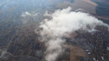 Fırtınadan önce, şişkin kümülüs bulutlarıyla kaplı uzak şehrin yüksek irtifasından gelen hava manzarası. Bulutlu havada uçak manzarası
