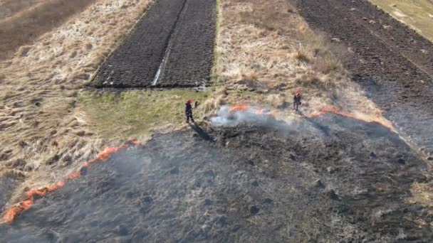 Vista aérea de bombeiros extinguindo campo de pastagens queimando com fogo vermelho durante a estação seca. Conceito de catástrofe natural e alterações climáticas — Vídeo de Stock