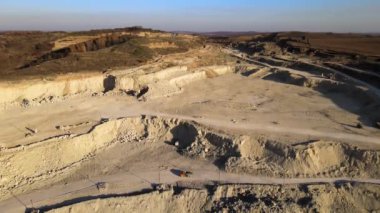 Kazı araçları ve çöp kamyonlarıyla inşaat endüstrisi için kireçtaşı malzemelerinin açık maden sahasının hava görüntüsü