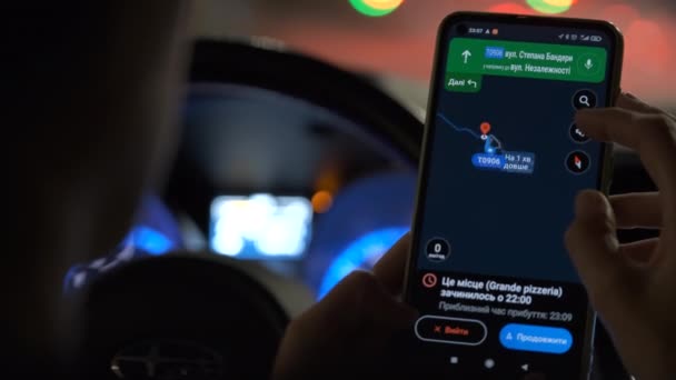 Primo piano delle mani del conducente che tengono il cellulare con l'app di navigazione di Google Maps in cerca di direzione con lampioni sfocati in città sullo sfondo di notte — Video Stock