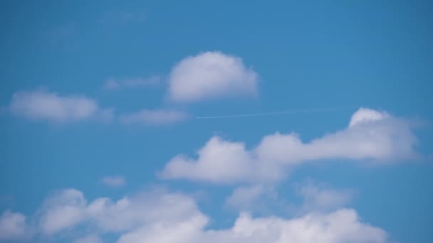 Avión a reacción de pasajeros lejano volando a gran altitud en el cielo azul con nubes blancas dejando rastro de humo de la estela detrás. Concepto de viaje aéreo — Vídeos de Stock