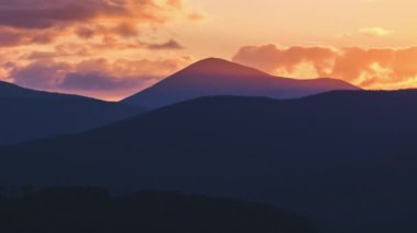 Güzel bir akşam panoramik manzarası. Gün batımında uzak dağ tepeleri üzerinde parlak batan güneş.
