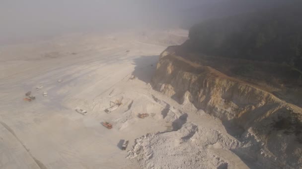 Вид с воздуха на открытую шахту добычи известняковых материалов для строительной промышленности с экскаваторами и самосвалами — стоковое видео