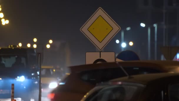 Señales de tráfico rotondas con coches borrosos en el tráfico urbano por la noche. Concepto de transporte urbano — Vídeo de stock