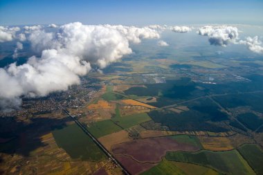 Fırtınadan önce, şişkin kümülüs bulutlarıyla kaplı uzak şehrin yüksek irtifasından gelen hava manzarası. Bulutlu havada uçak manzarası