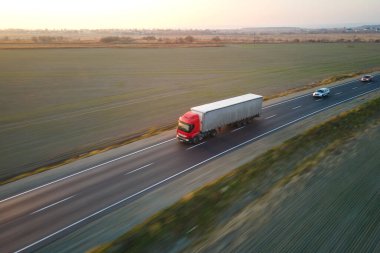 Bulanık hızlı hareket eden yarı kamyonun hava görüntüsü. Kargo karavanıyla birlikte akşamları otobanda mal taşırken görülüyor. Teslimat ulaşım ve lojistik kavramı