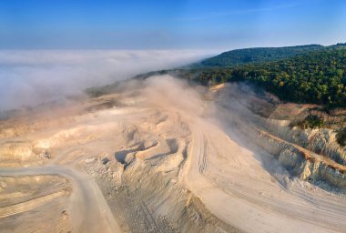 Kazı araçları ve çöp kamyonları ile inşaat endüstrisi için kireçtaşı malzemelerinin açık çukur madenciliğinin hava görüntüsü