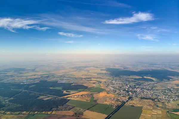 Vista aérea da janela do avião em alta altitude da terra coberta com camada fina branca de névoa enevoada e nuvens distantes ao pôr do sol — Fotografia de Stock