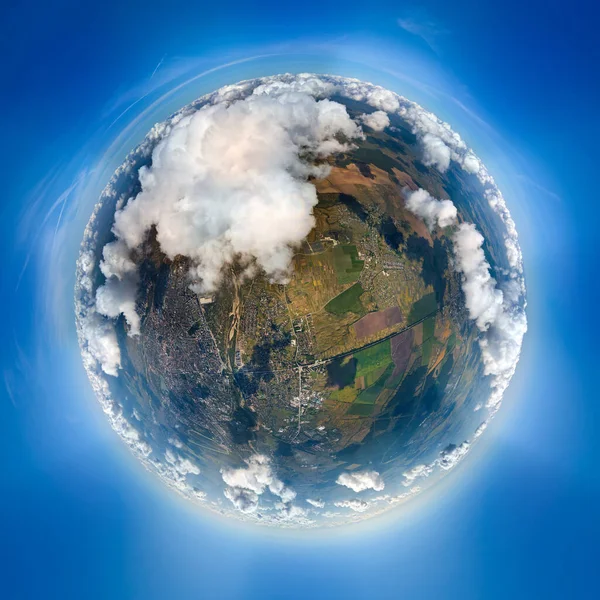 Luftaufnahme aus großer Höhe von einem kleinen Planeten mit einer entfernten Stadt, die vor einem Regensturm mit geschwollenen Kumuluswolken bedeckt ist. Blick aus dem Flugzeug auf bewölkte Landschaft — Stockfoto
