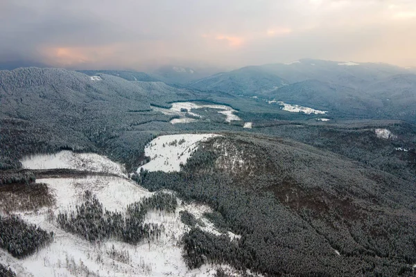 Luftaufnahme der kargen Winterlandschaft mit Hügeln mit immergrünem Kiefernwald nach starkem Schneefall am kalten ruhigen Abend bedeckt — Stockfoto
